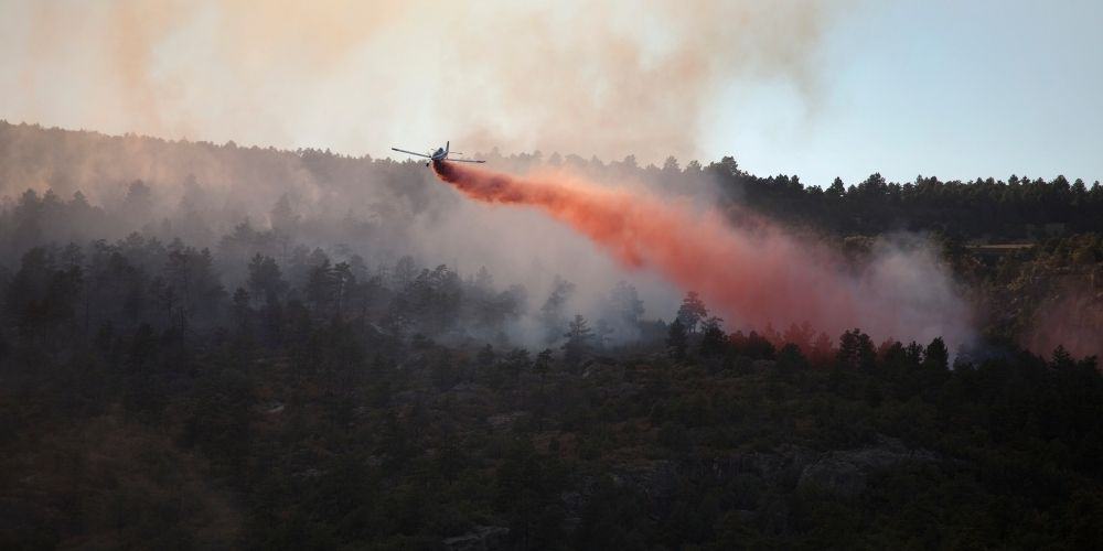 airplane putting out wildfire with fire retardant chemicals