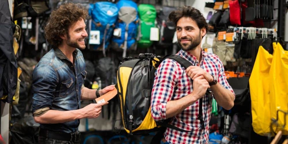 man comparing backpacks in a store